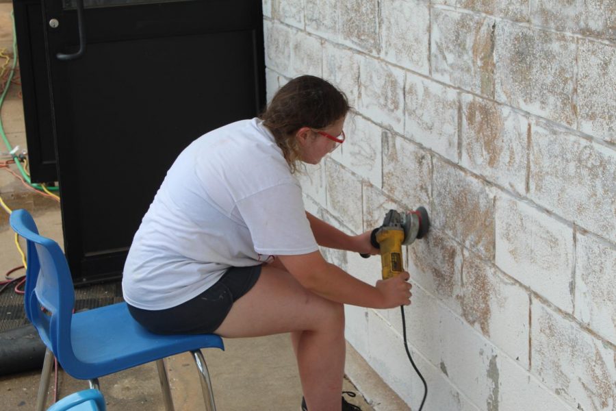 Rylie Pass grinds off loose paint from the front of the Bray-Doyle gym. 